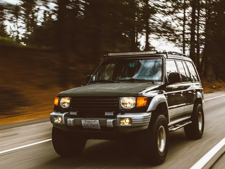 An older SUV on a tree-lined road