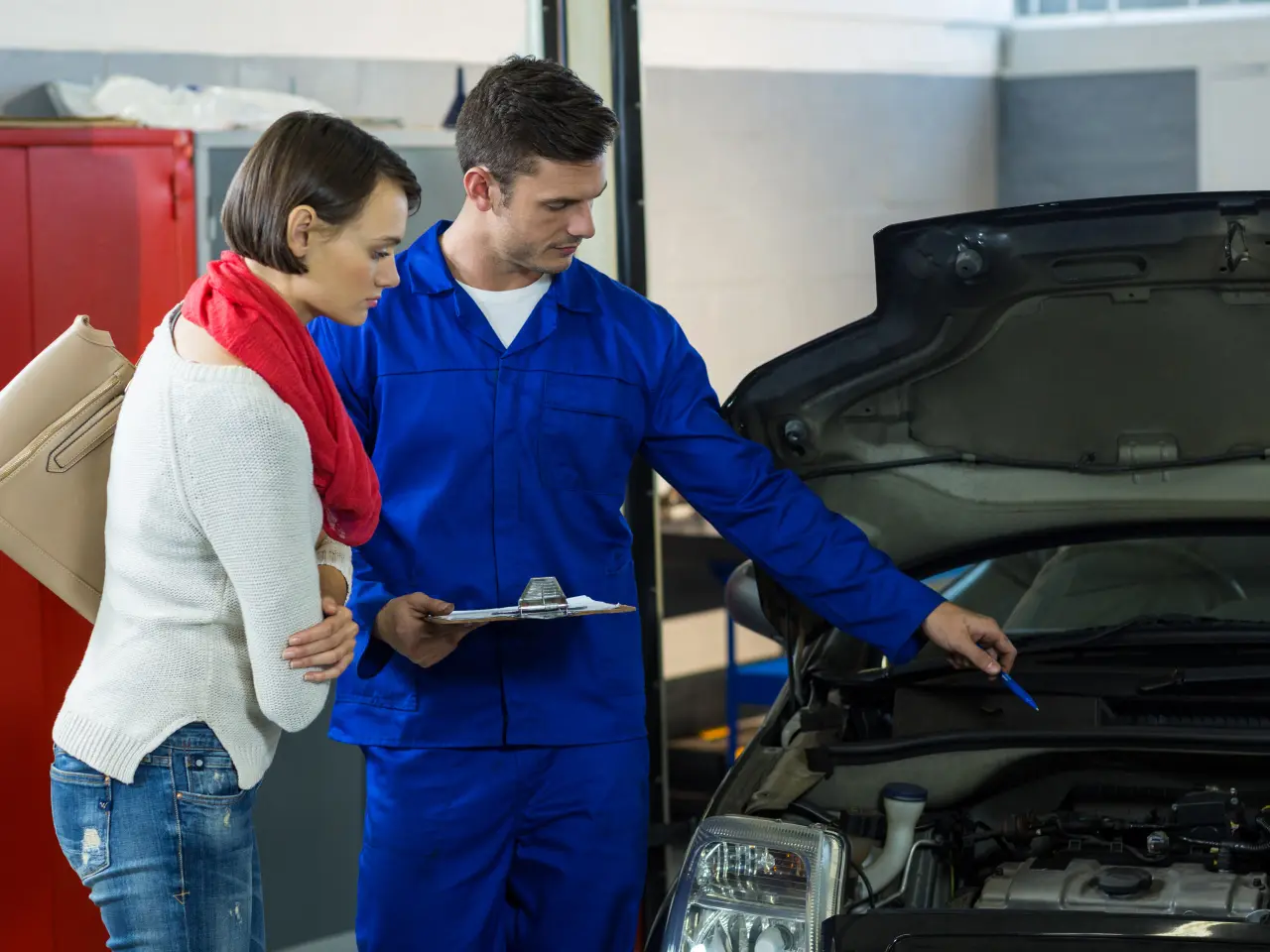 A mechanic showing a customer a problem under an open hood
